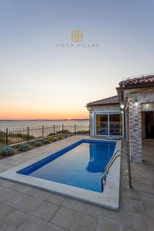 Blue loungers by the private pool at sunset with the lit Sweet Life villa facade
