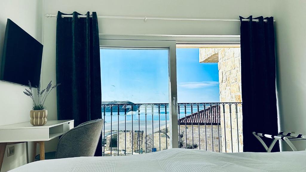 Bedroom with TV, desk and sea view through glass doors in Lovers Nest