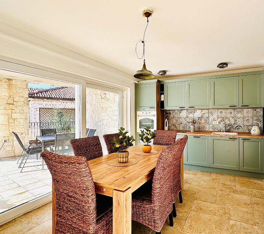Wooden dining table beside the green kitchen with a terrace view in Endless Summer